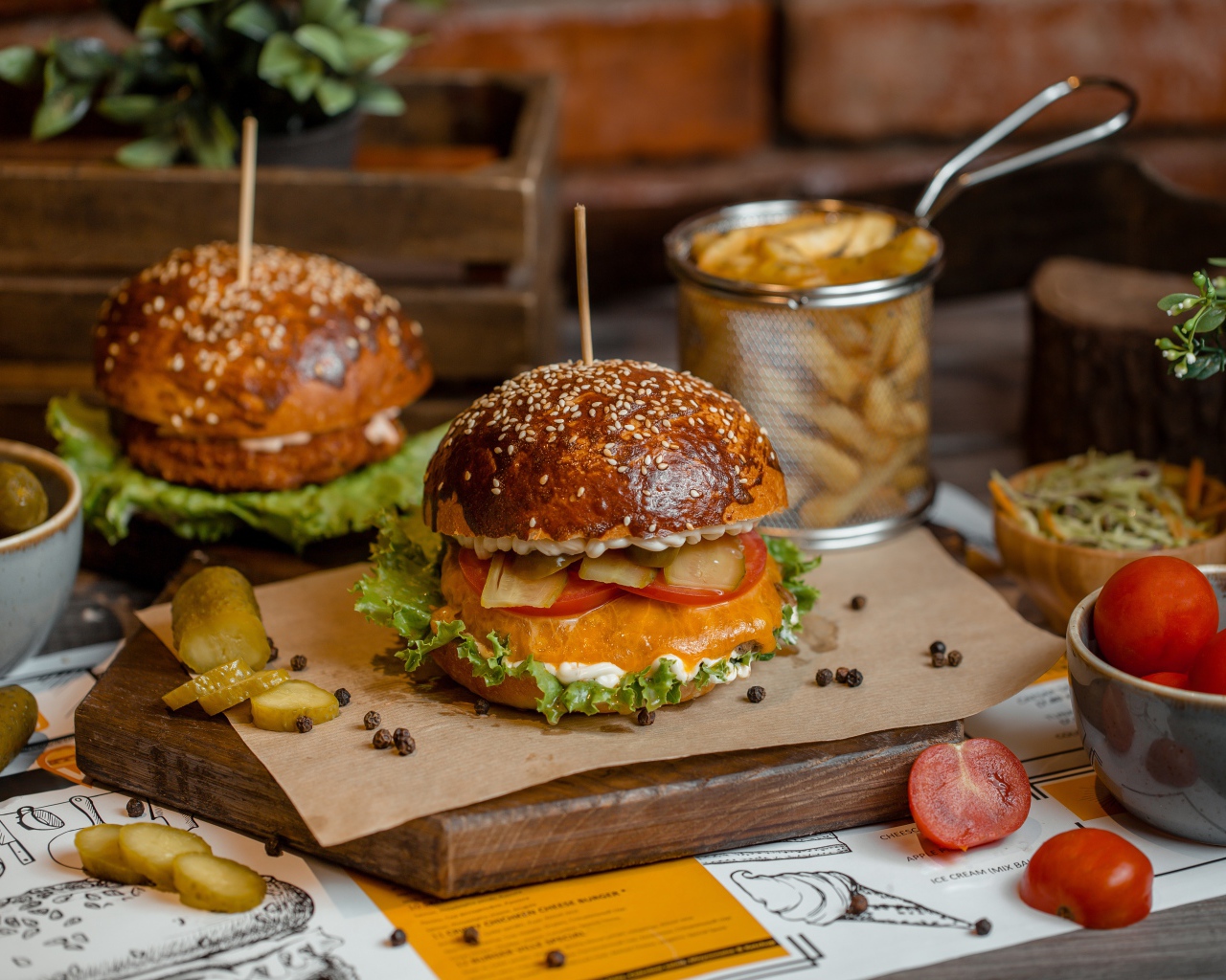 Гамбургеры на столе с помидорами, картофелем фри и солеными огурцами