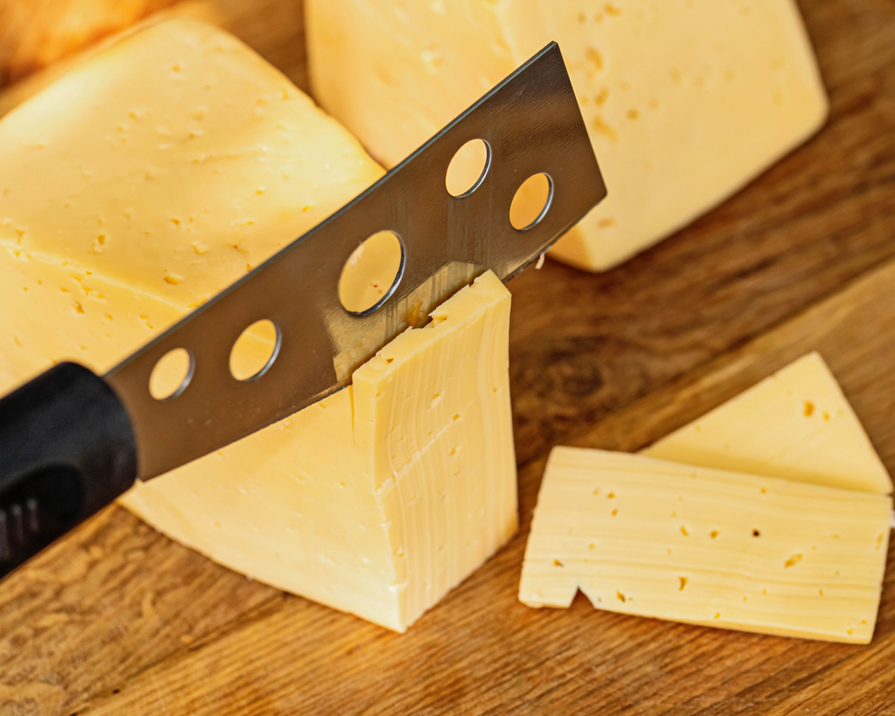 Твердый сыр с ножом на столе