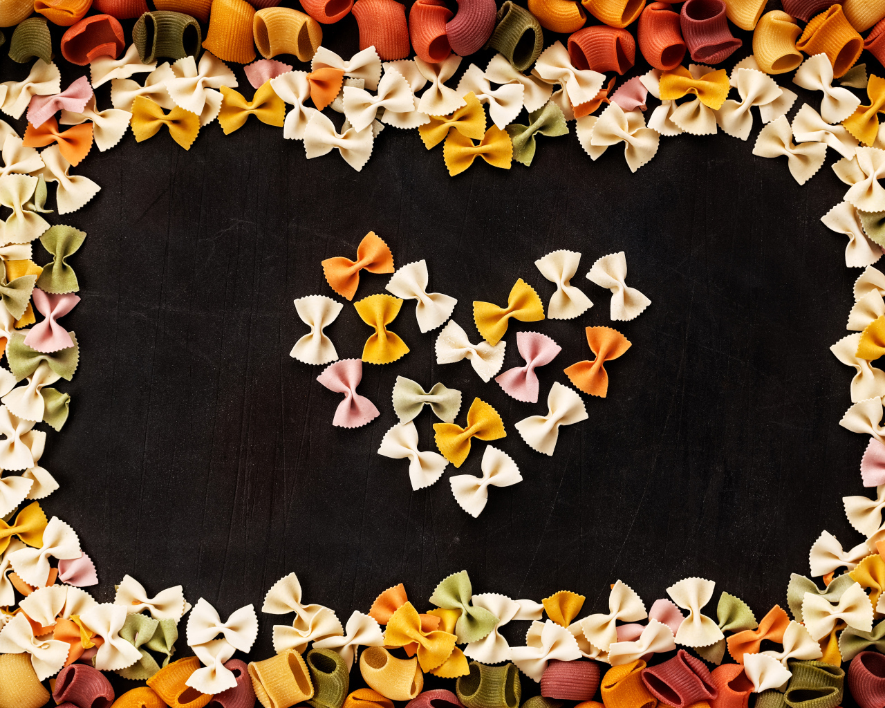 Сердце из разноцветных макарон на черном столе 