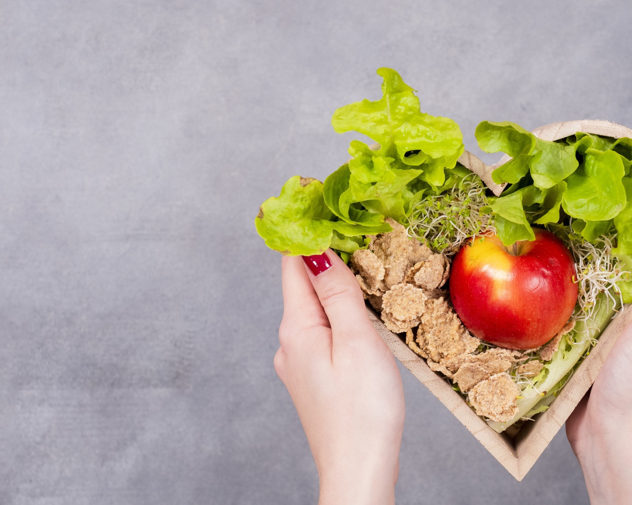 Коробка в форме сердца с яблоком и листьями салата 