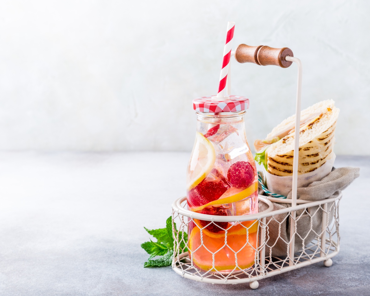 Банка с лимонадом в маленькой корзине с сэндвичем 