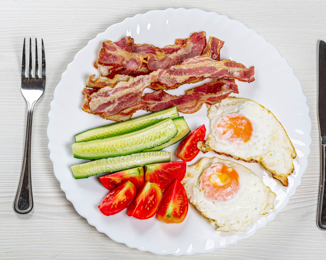 Большая белая тарелка с беконом, огурцами, помидорами и яичницей 