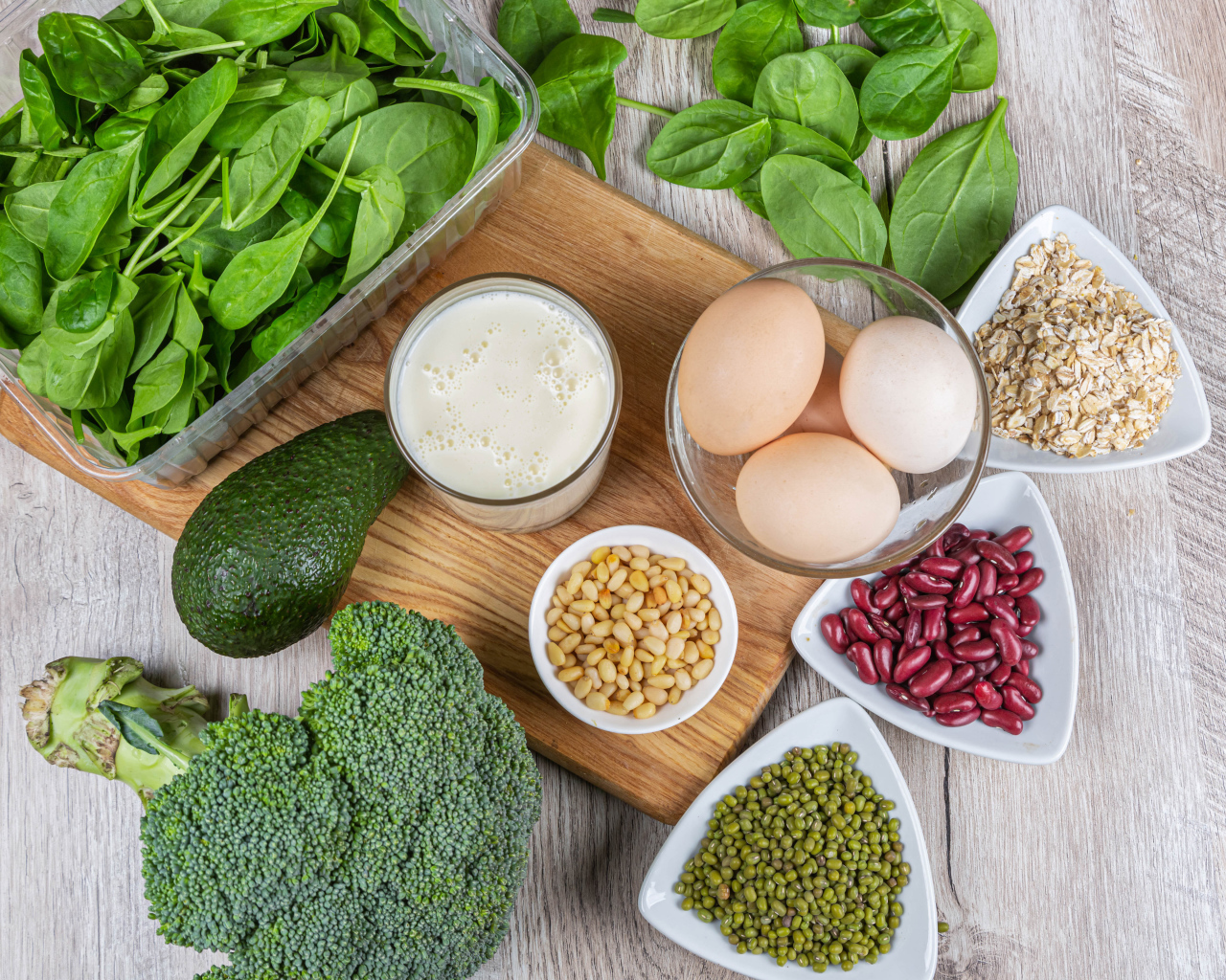Бобовые, авокадо, базилик, яйца молоко и брокколи на столе