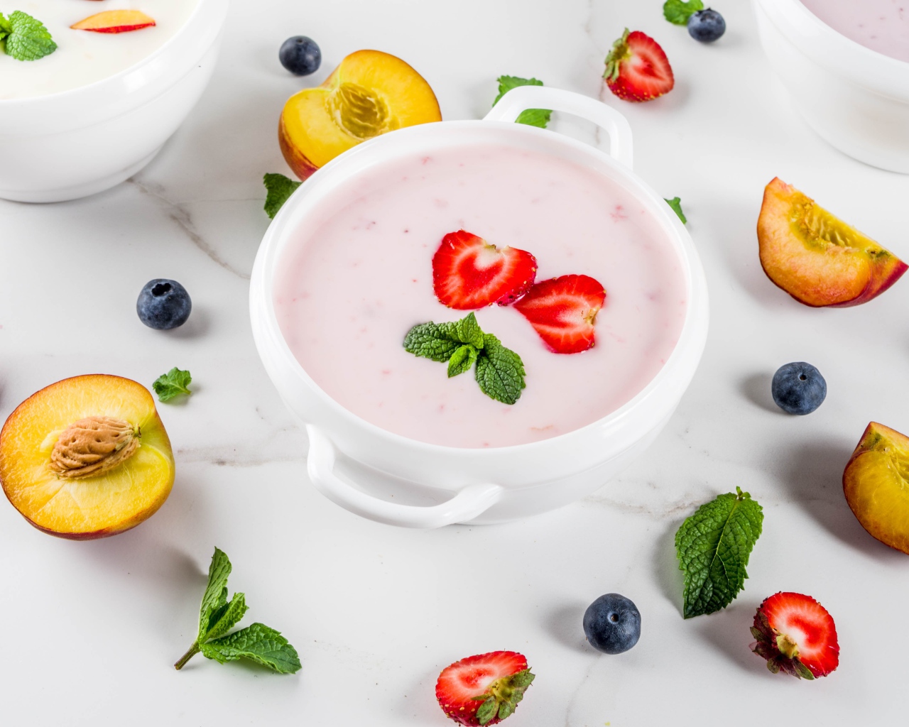 Молочный суп в тарелке на столе с ягодами и нектарином