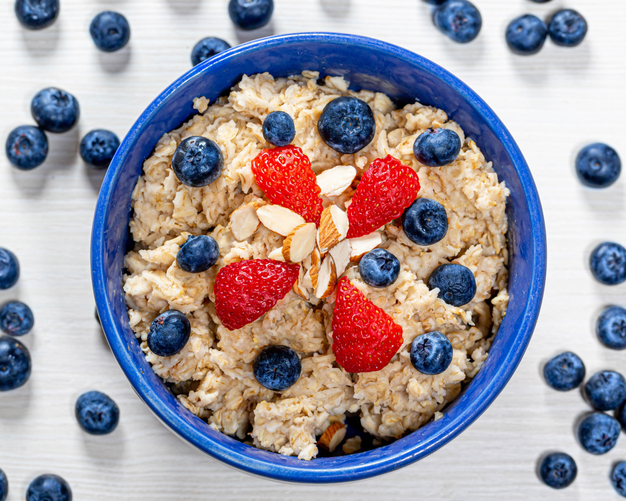 Овсяная каша в тарелке с ягодами черники и клубники 