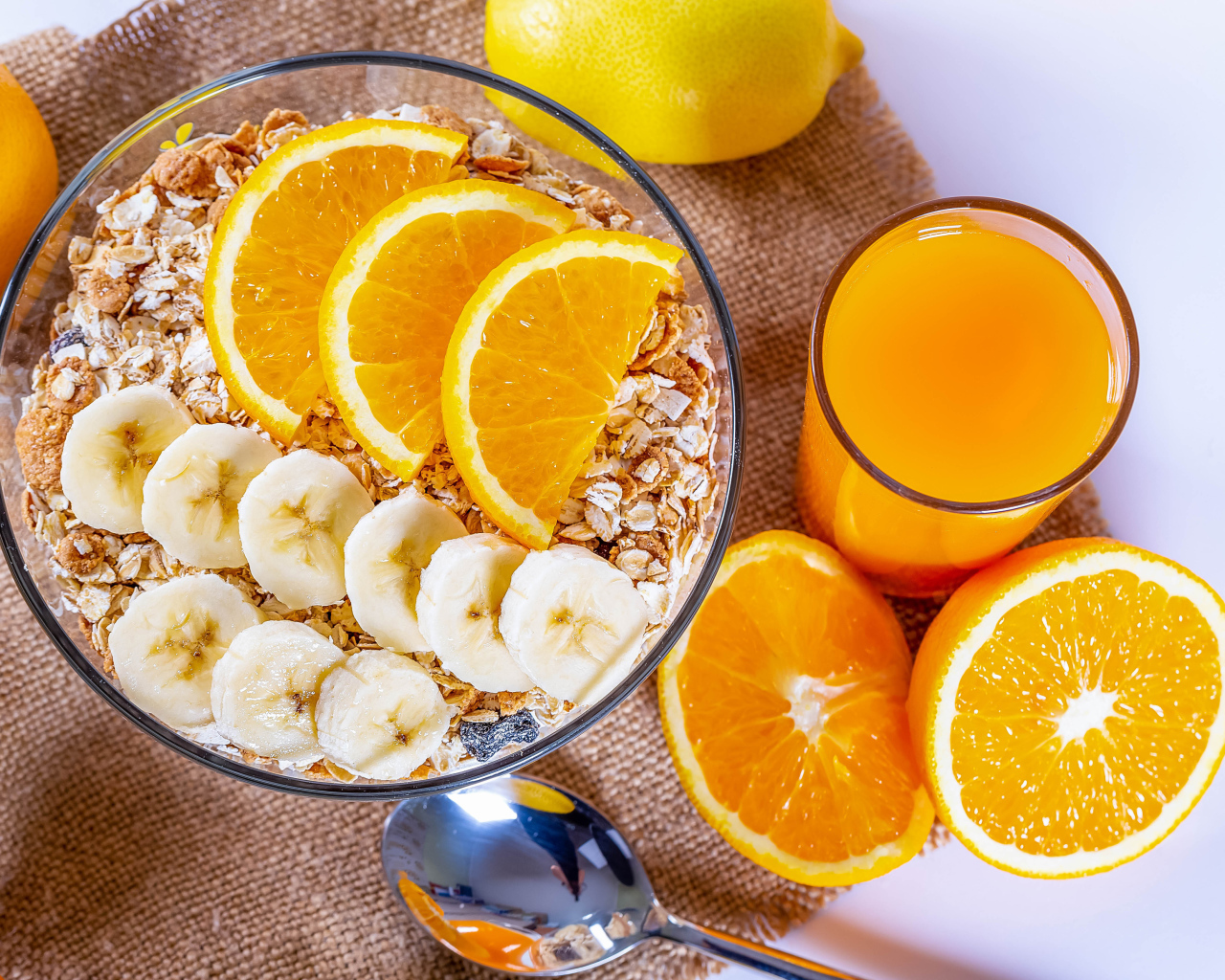 Овсяные хлопья в тарелке с кусочками банана и апельсина на столе с соком