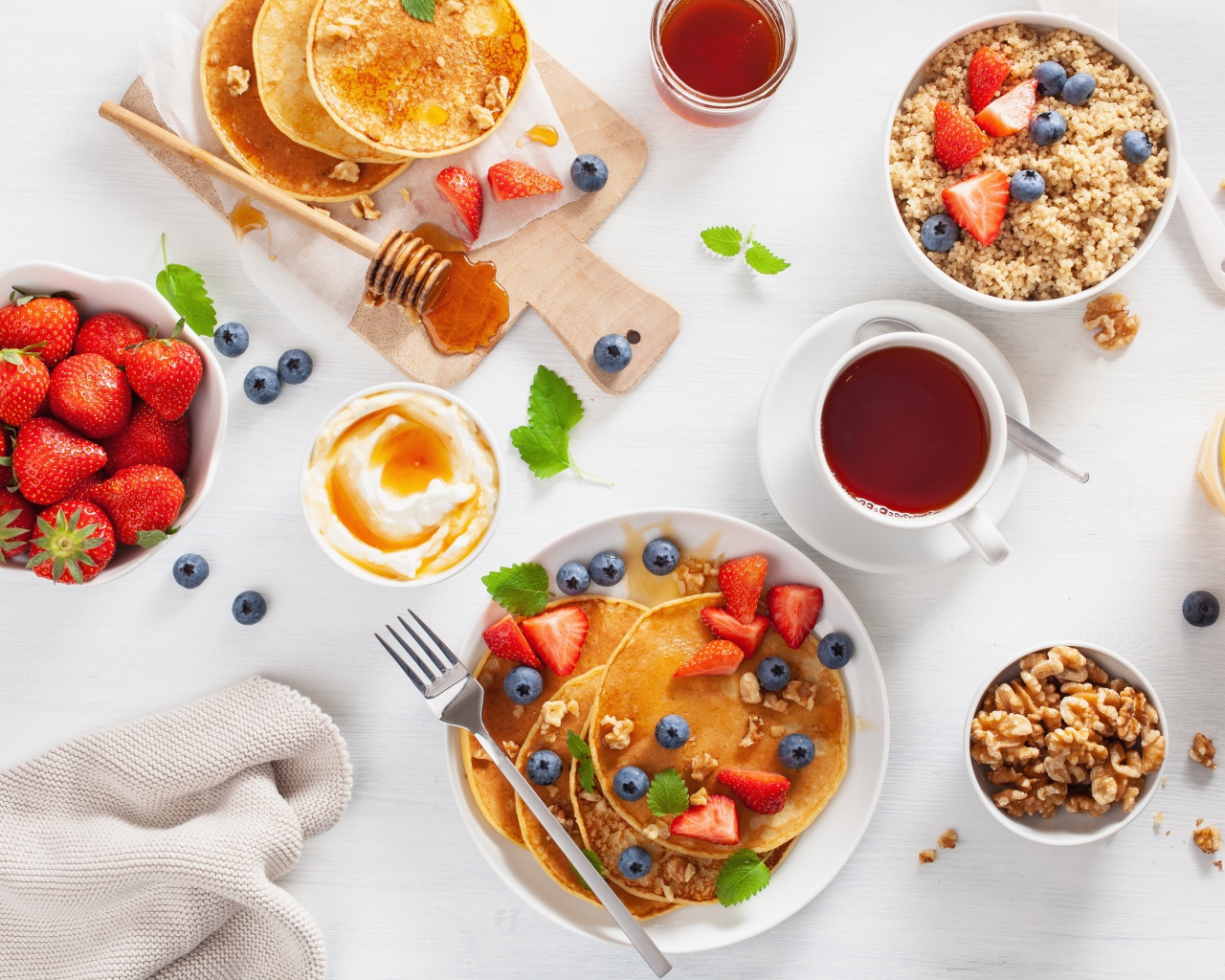 Оладьи с ягодами на столе с соком, чаем и мюсли на завтрак 