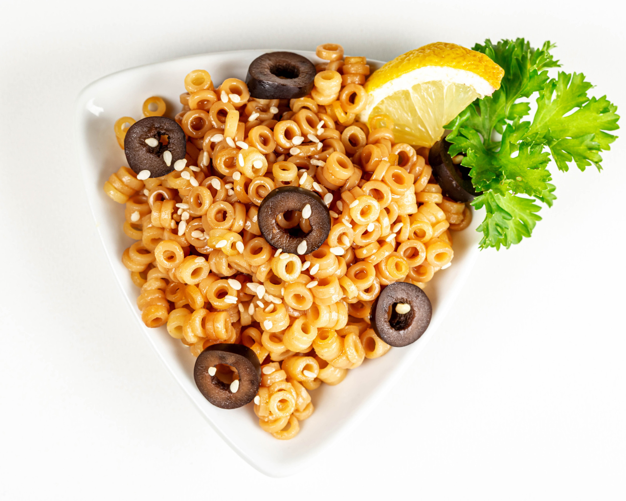 Макароны на тарелке с оливками и лимоном