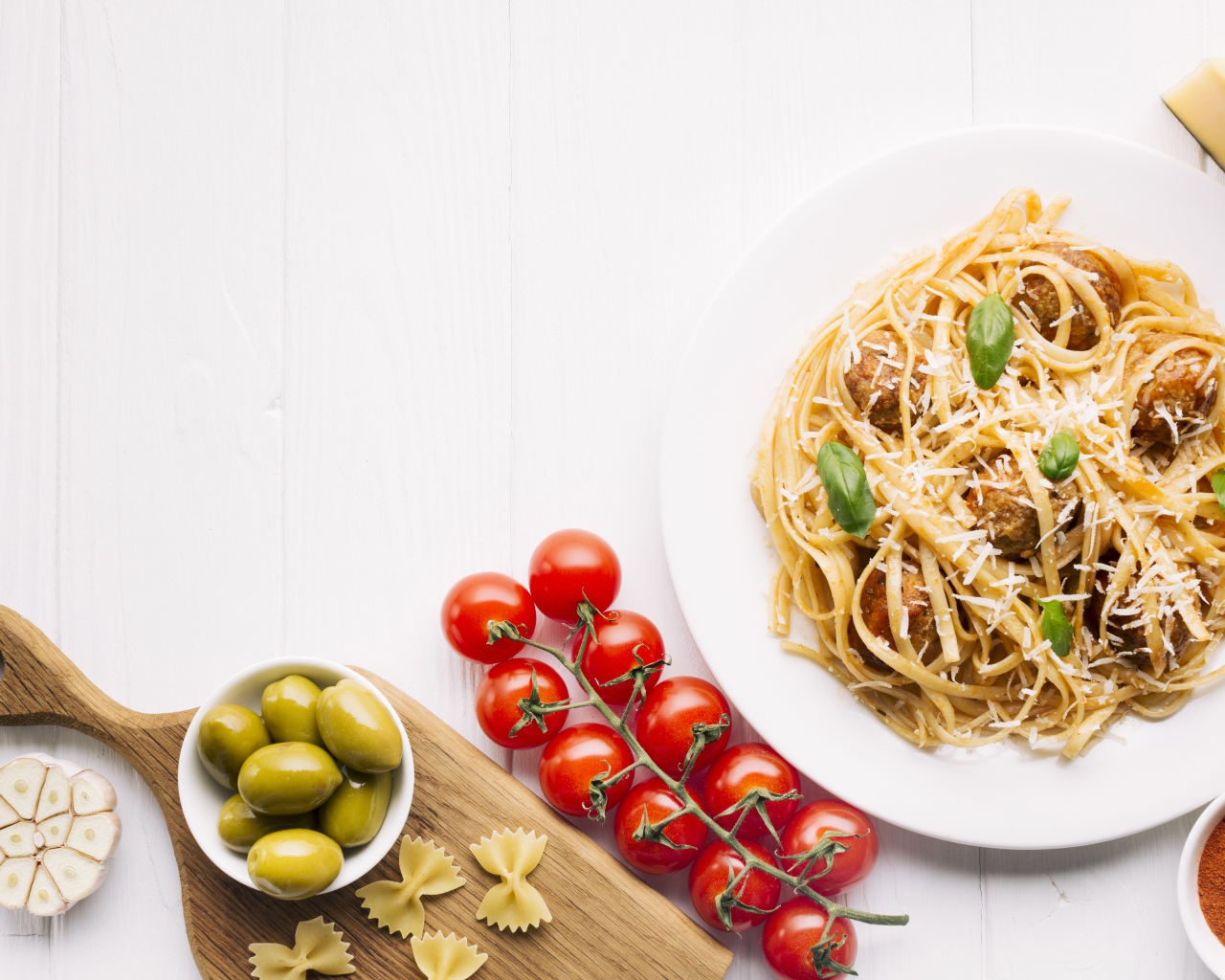 Паста с фрикадельками на столе с помидорами и оливками