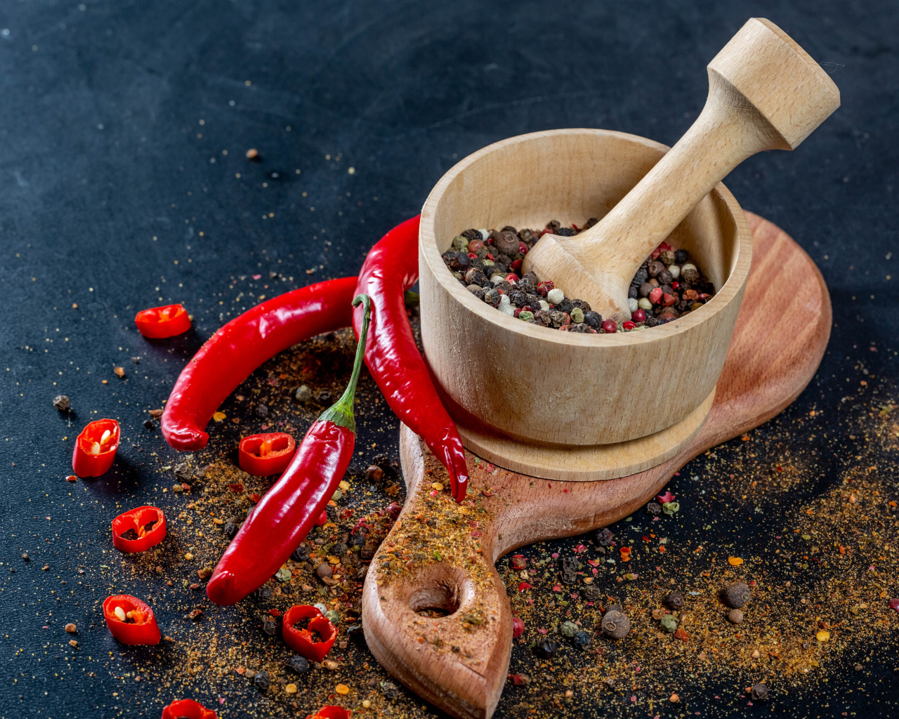 Перец горошком в ступке на столе с острым перцем