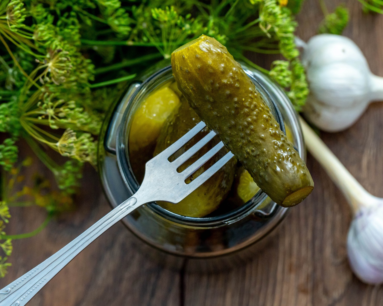 Маринованные огурцы в банке на столе с чесноком и укропом