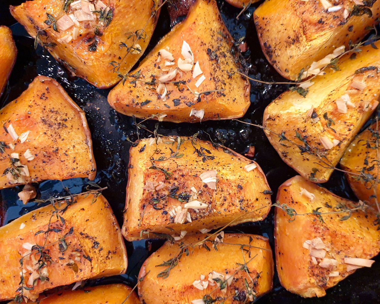 Куски жареной тыквы со специями на сковороде 