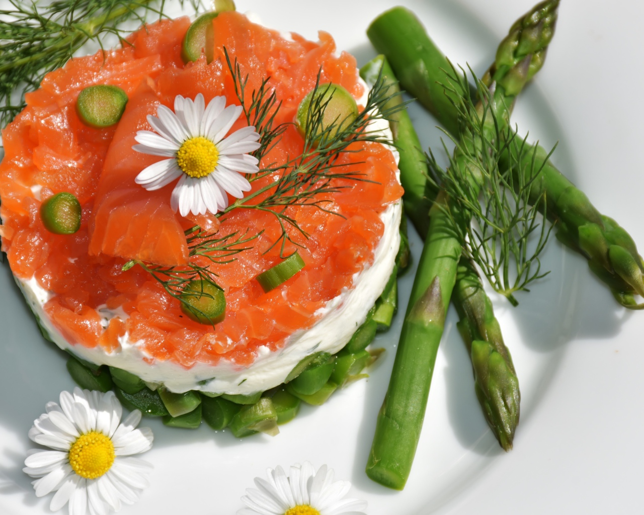 Салат с красной рыбой на тарелке со спаржей, укропом и цветами ромашки