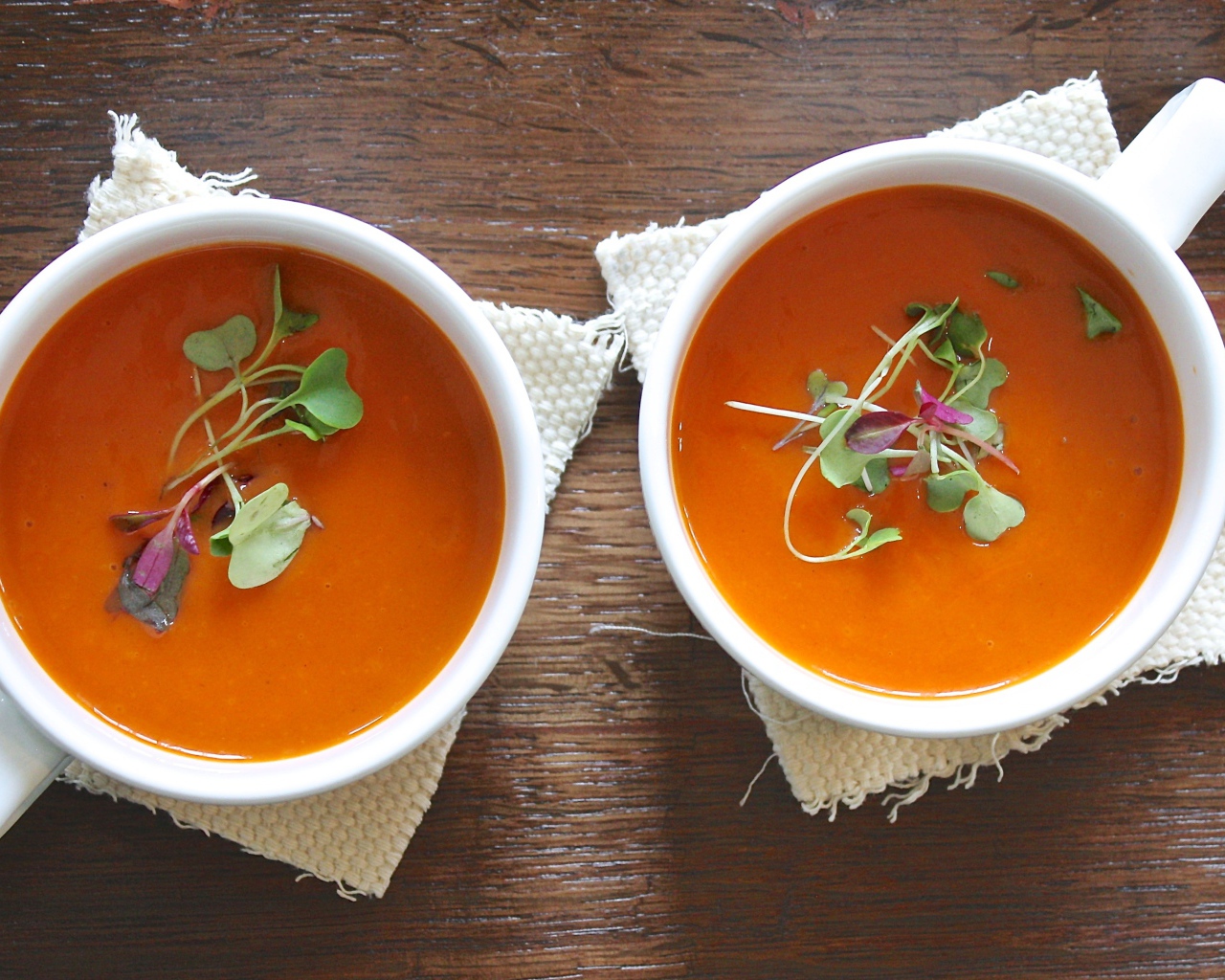 Красный суп пюре в белых чашках на столе 