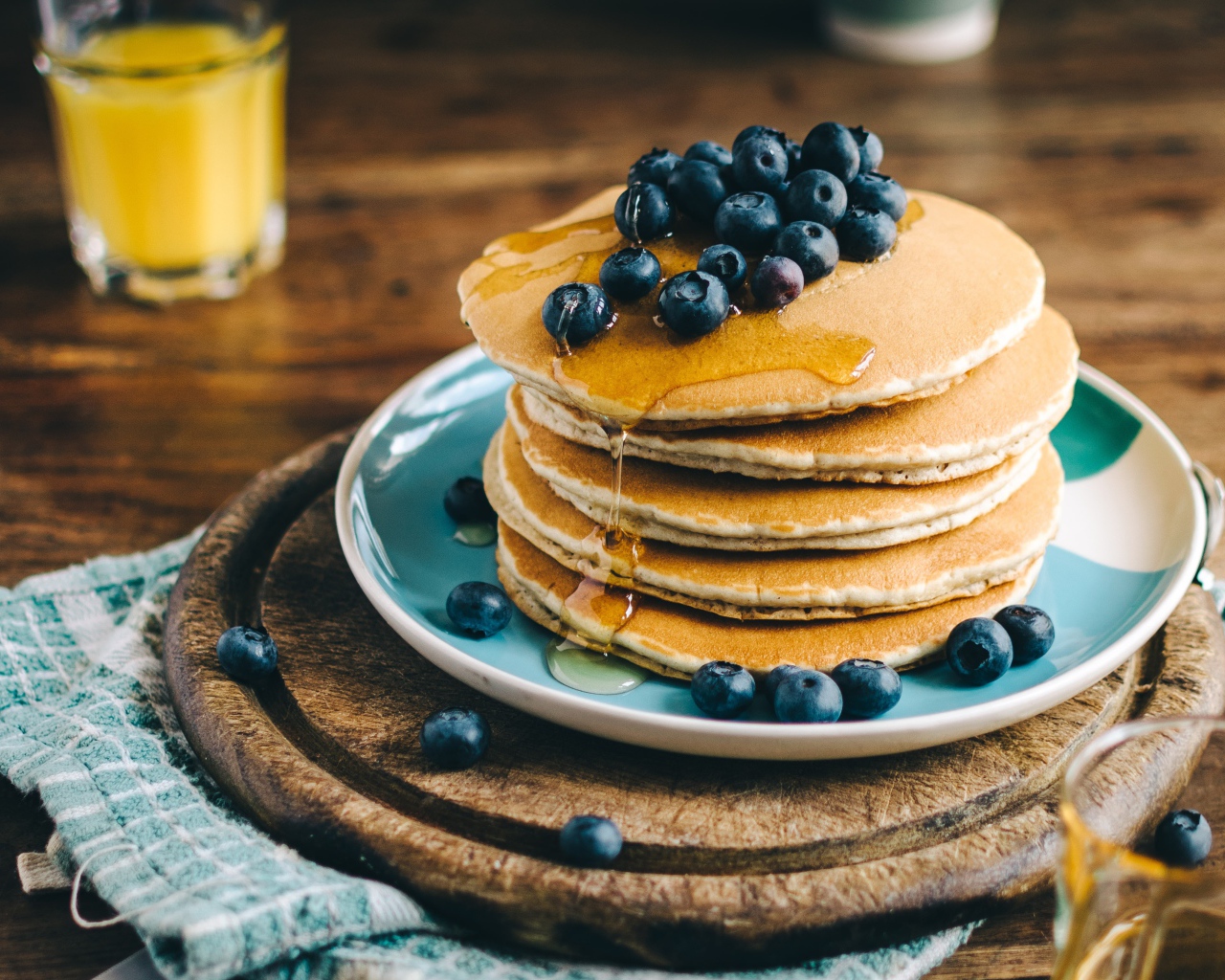 Румяные оладья на тарелке  с медом и ягодами черники 