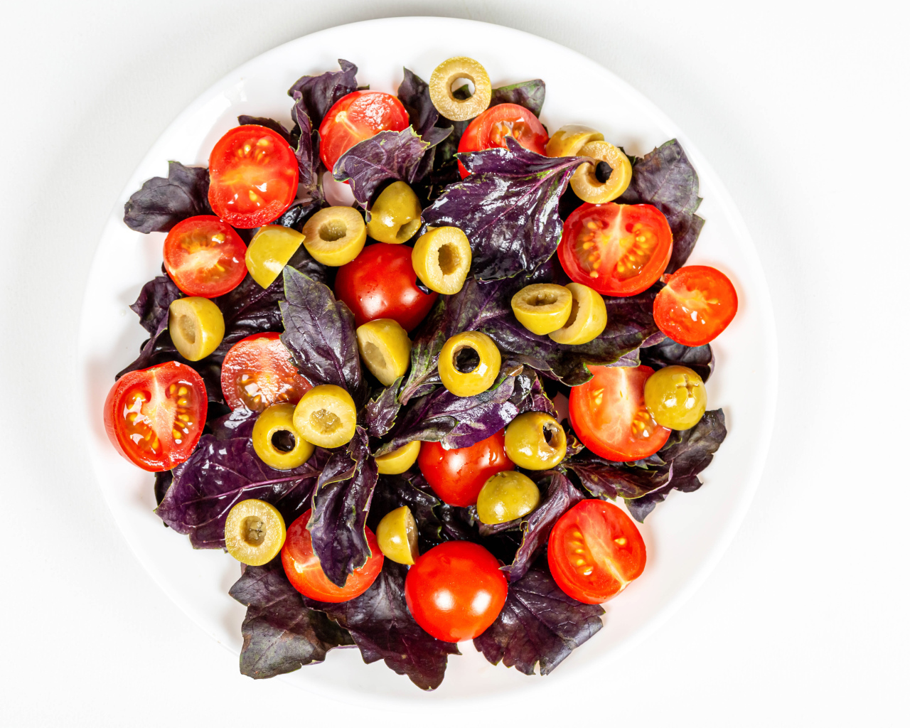 Салат с листьями базилика, помидорами и оливками на белом фоне