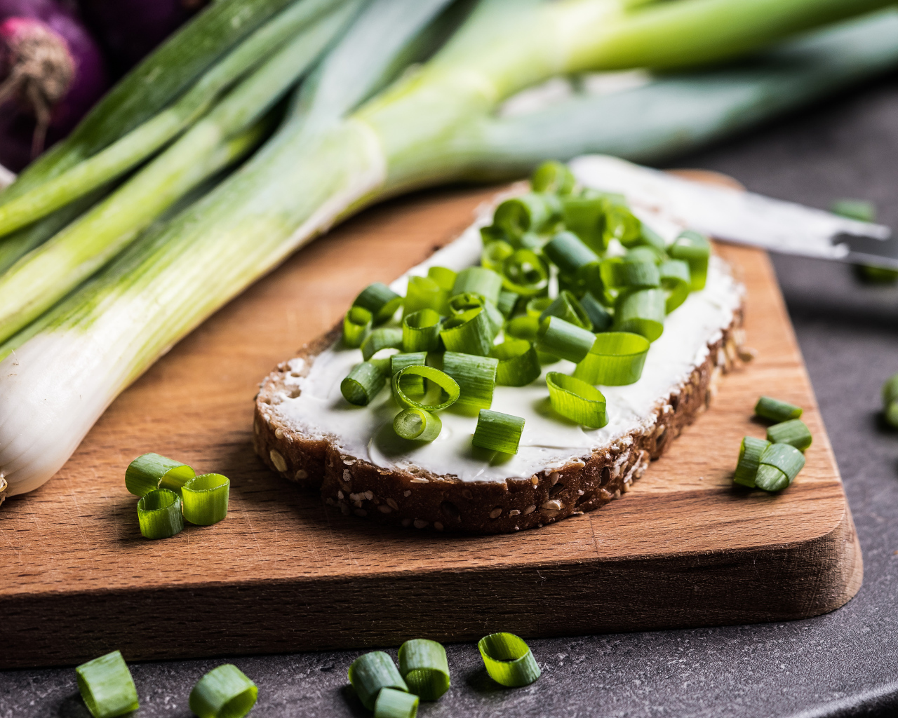 Бутерброд с маслом и зеленым луком на столе 