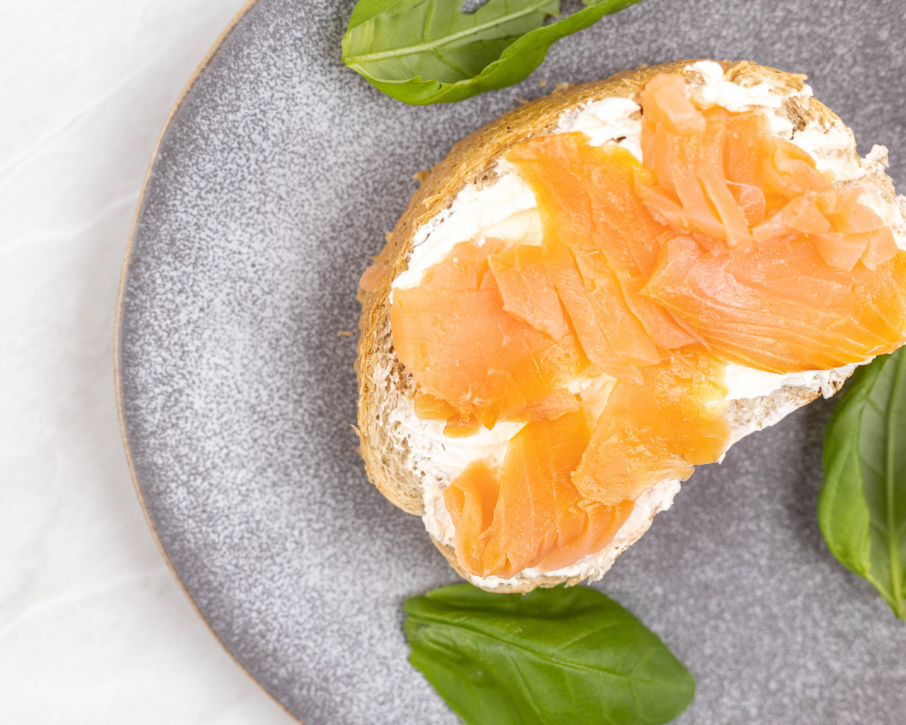 Бутерброд с сыром, красной рыбой и листьями базилика