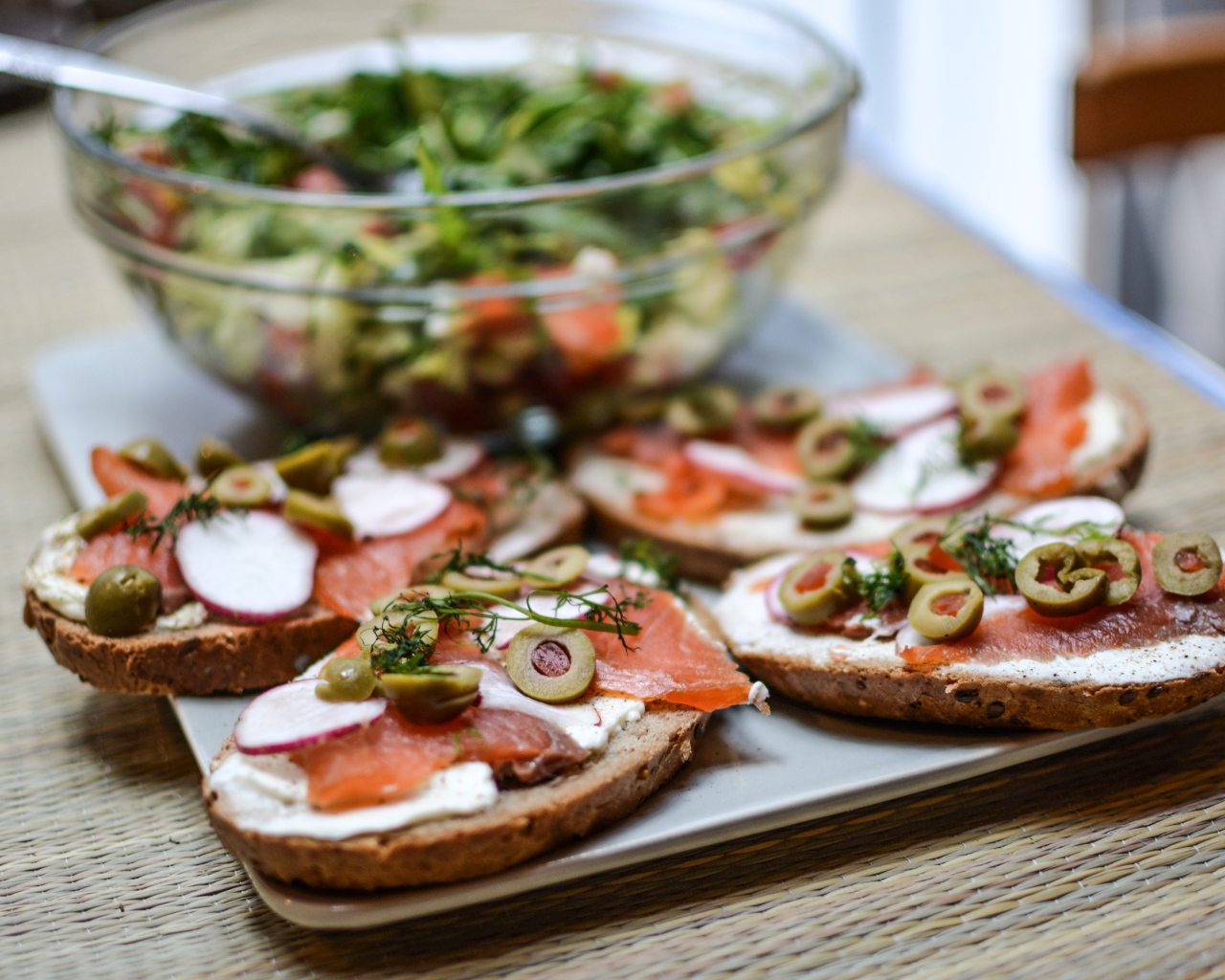 Бутерброды с маслом и красной рыбой на столе с салатом