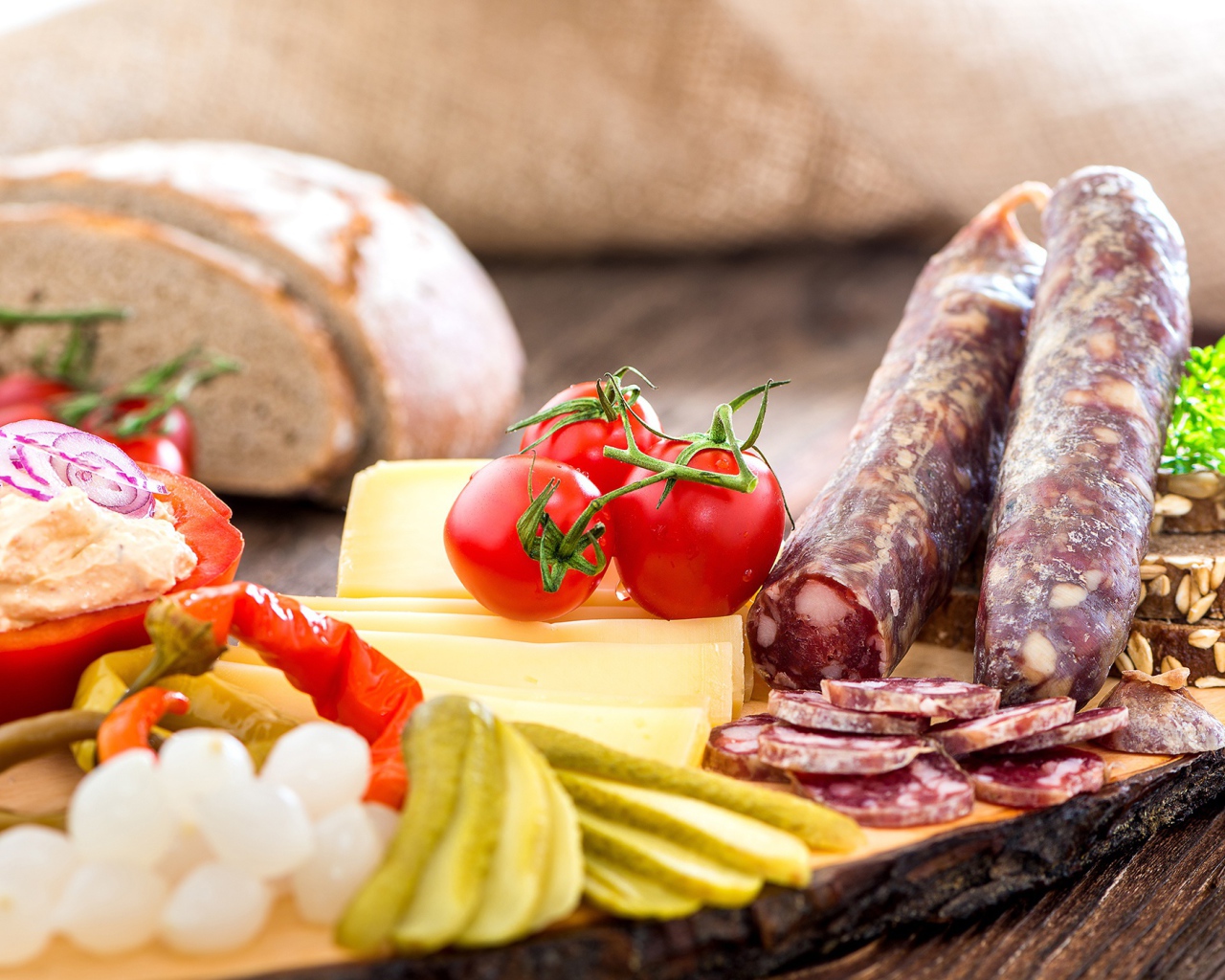 Колбаса на столе с огурцами, помидорами и перцем