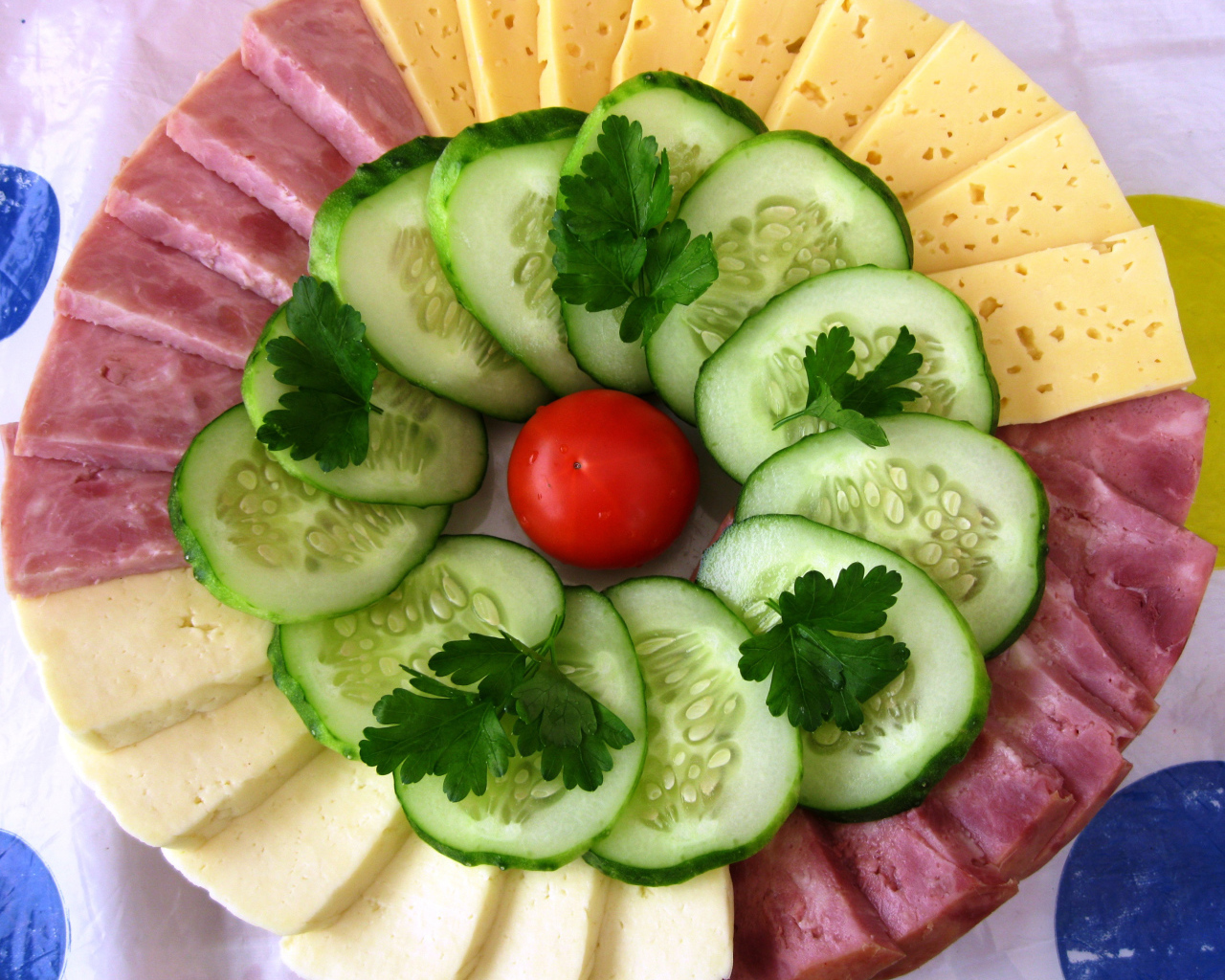 Сыр нарезанный, огурцы и ветчина на тарелке 