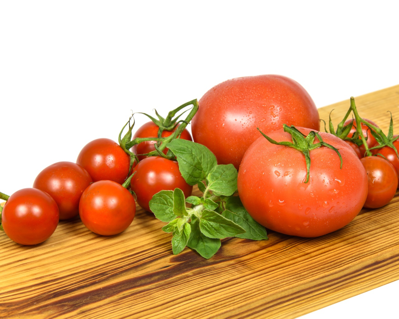 Маленькие и большие помидоры на деревянной доске 