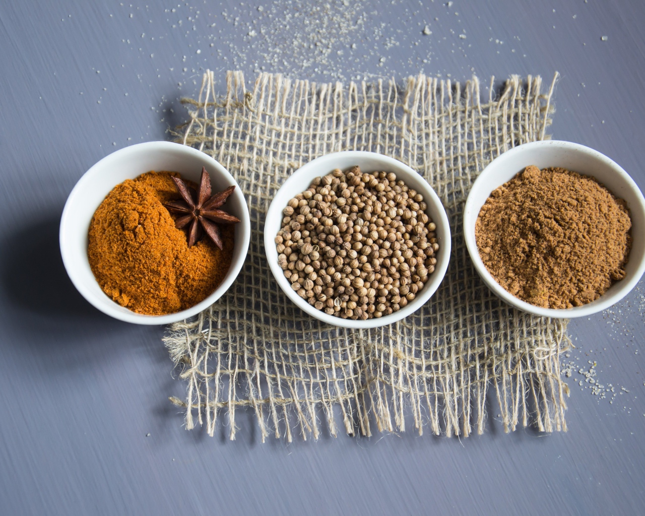 Специи в белых мисках на сером столе 