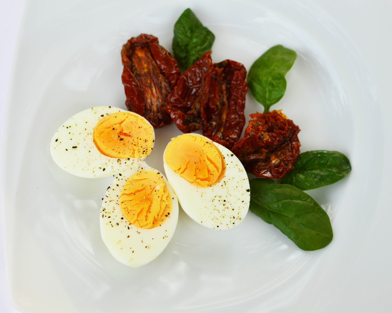 Вяленые помидоры на тарелке с базиликом и вареными яйцами