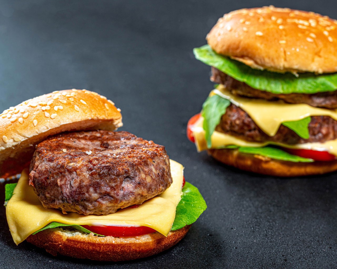 Два аппетитных гамбургера с сочной котлетой на сером фоне