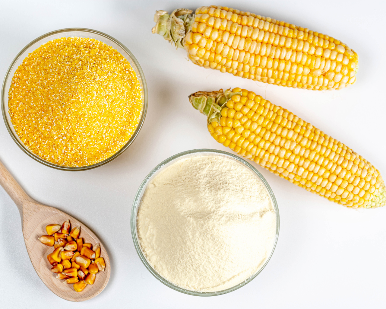 Два початка кукурузы на белом фоне с крупой и мукой 