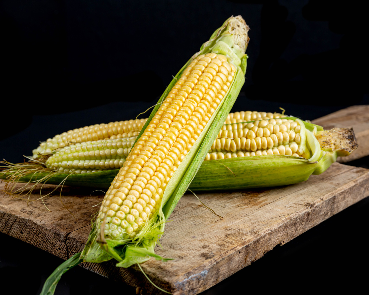 Два початка кукурузы на деревянной доске 