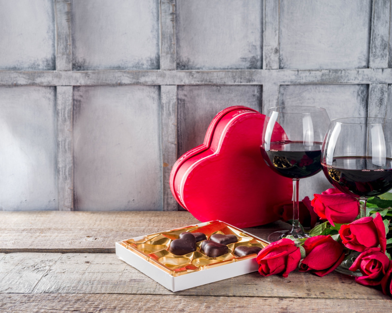 Два бокала вина, шоколадные конфеты и розы на столе для любимой 
