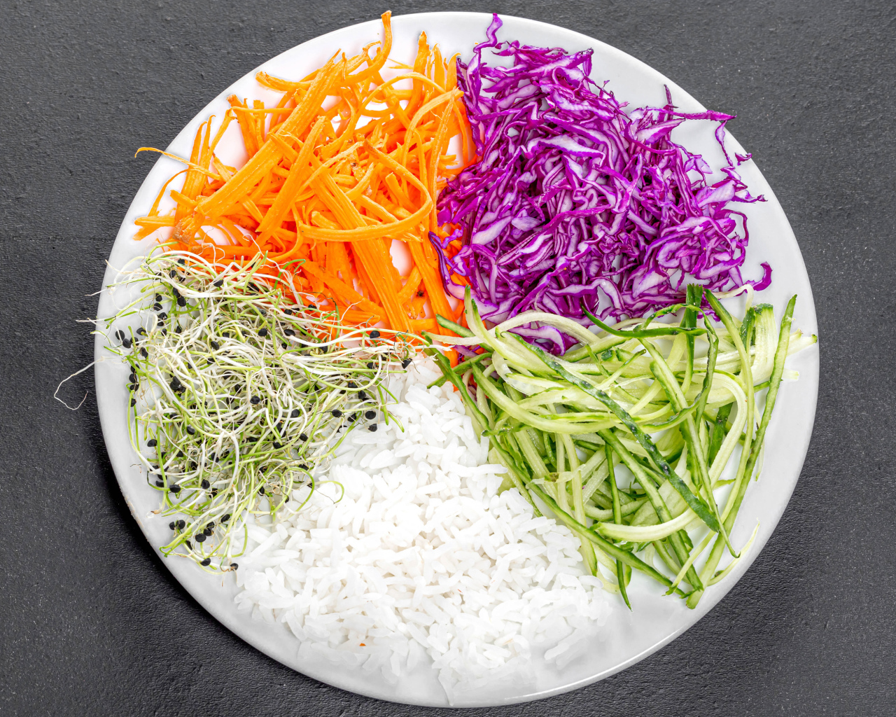Овощи с рисом на большой  белой тарелке на сером столе 