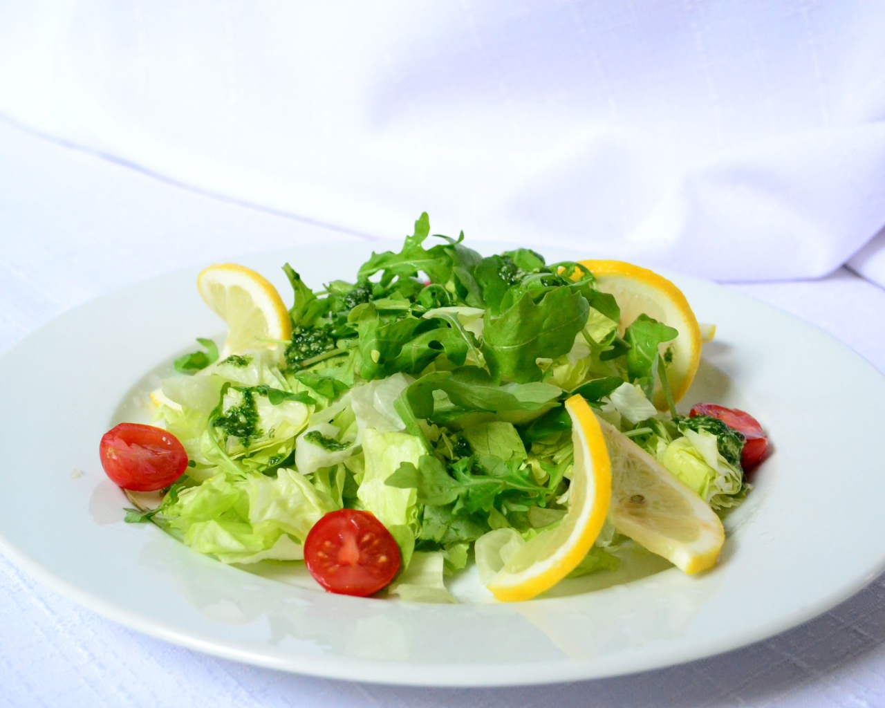 Белая тарелка со свежим зеленым салатом 
