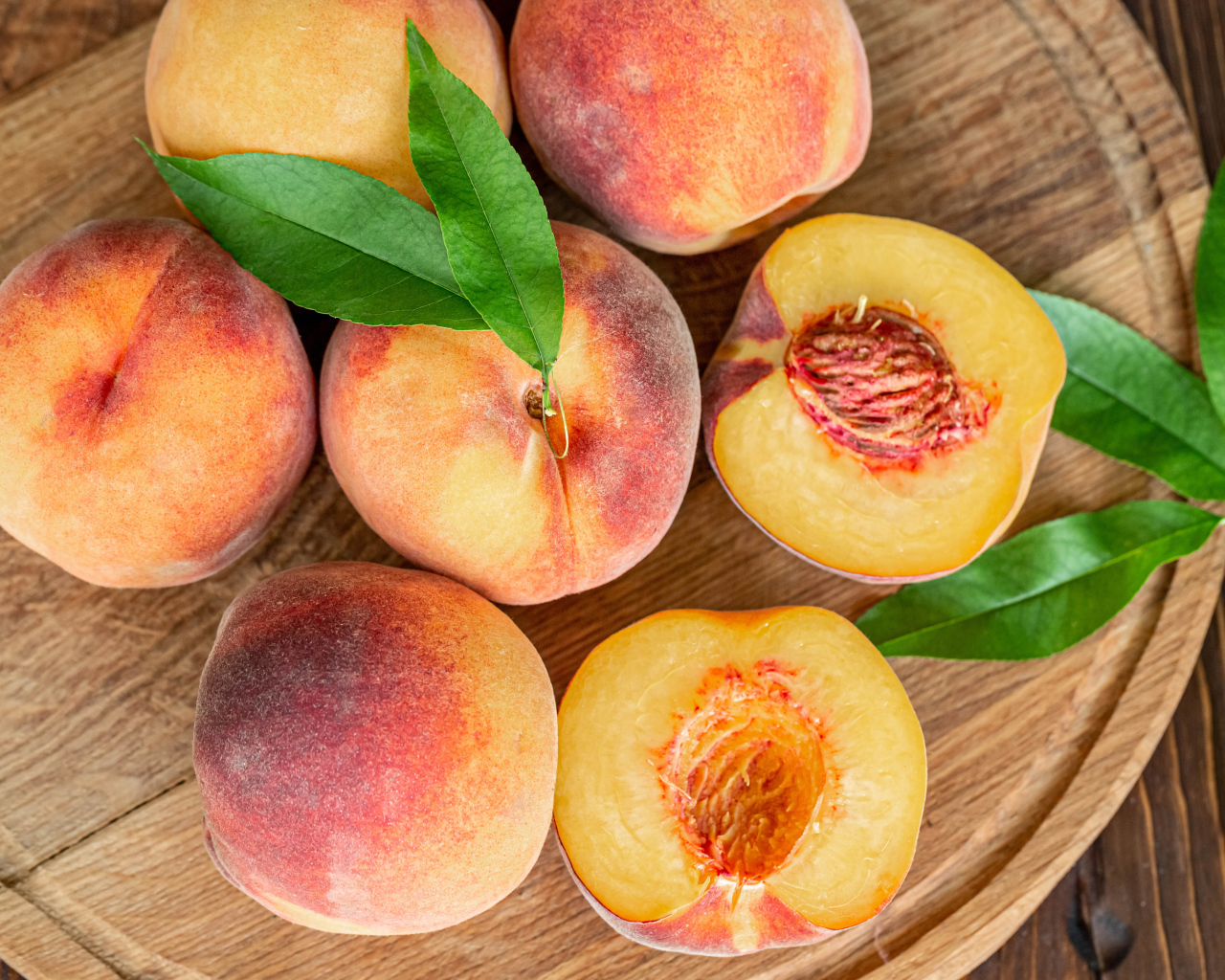 Аппетитные свежие персики на деревянной доске