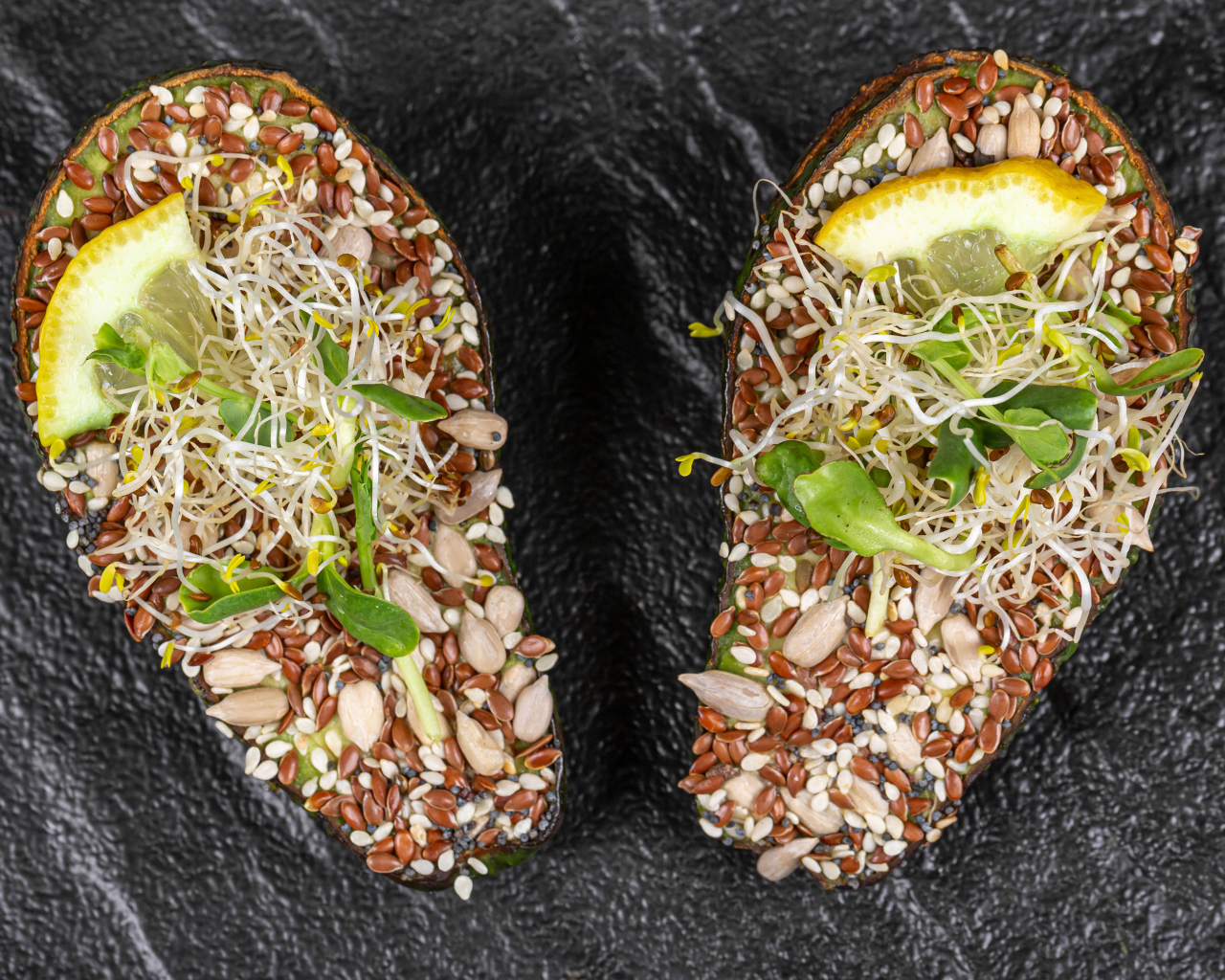 Половинки авокадо с проросшими зернами на столе