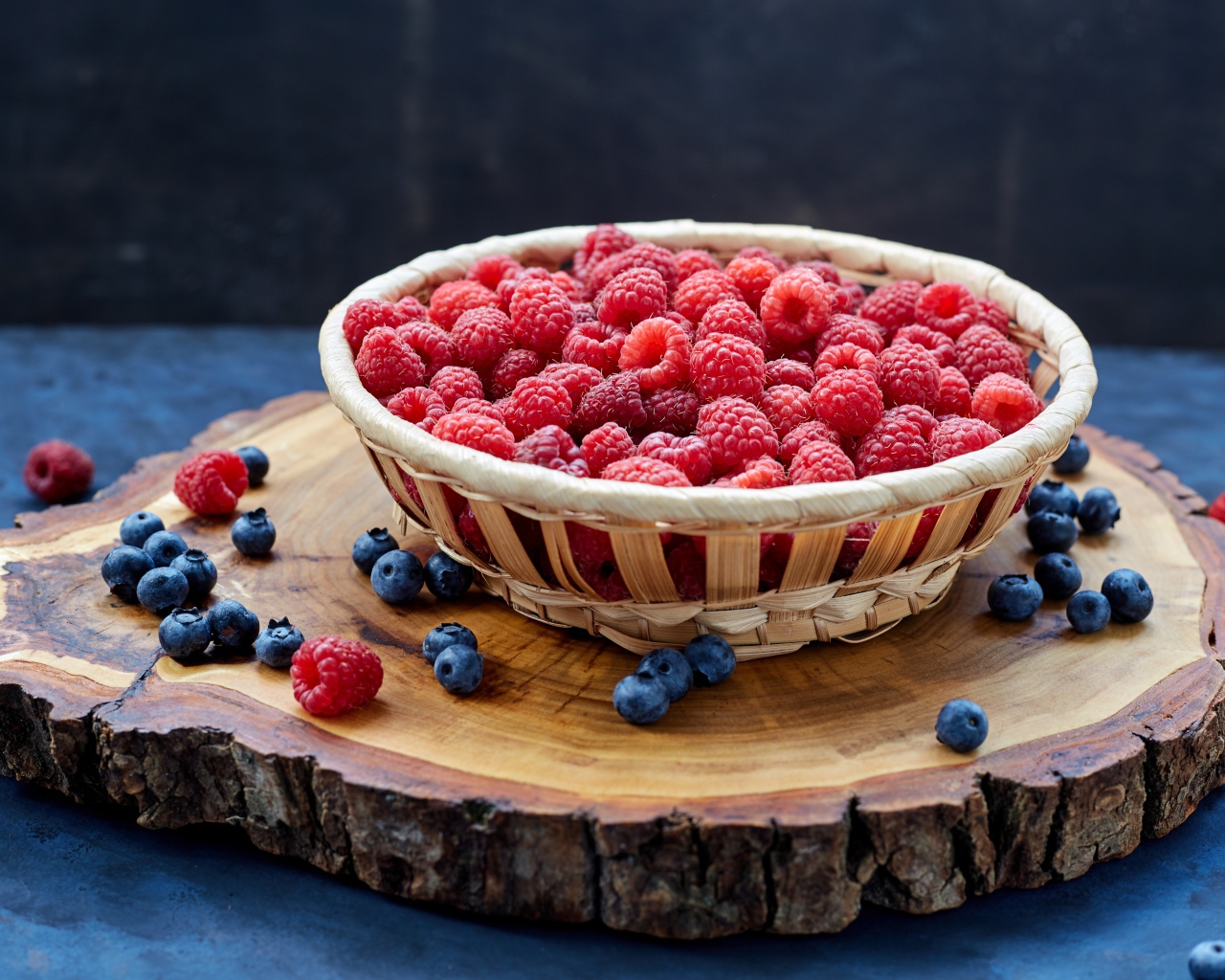 Корзинка с малиной на столе с ягодами черники