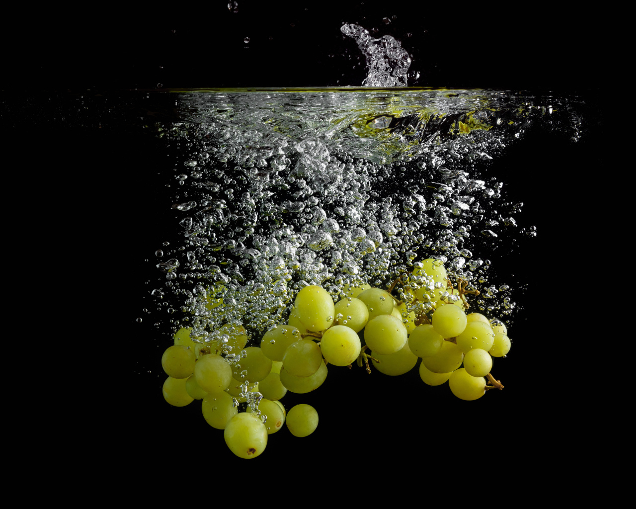 Ягоды белого винограда в воде на черном фоне