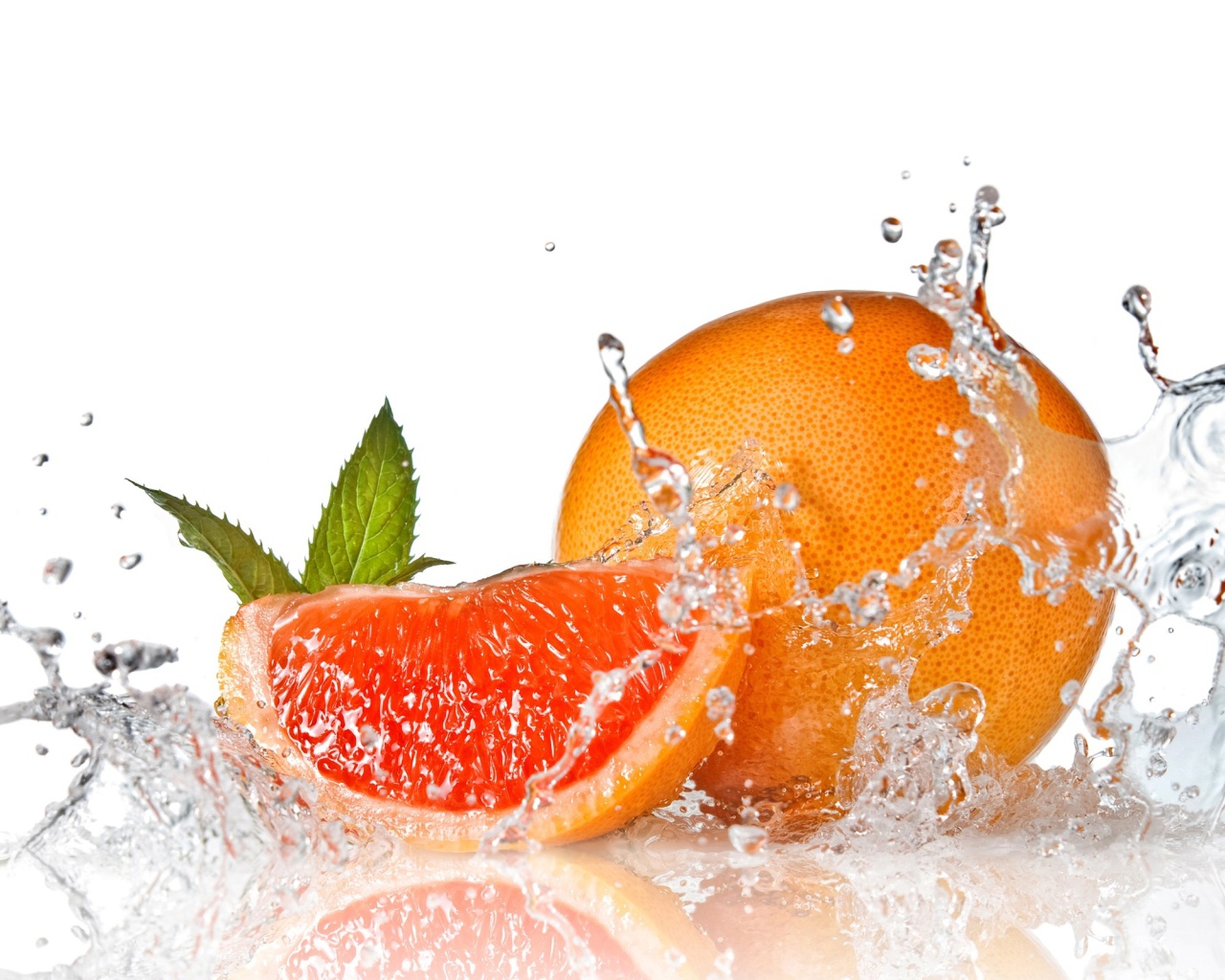 Большой спелый апельсин в брызгах воды на белом фоне