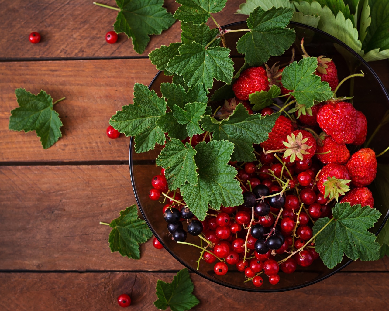 Ягоды смотродины в миске с клубникой и зелеными листьями