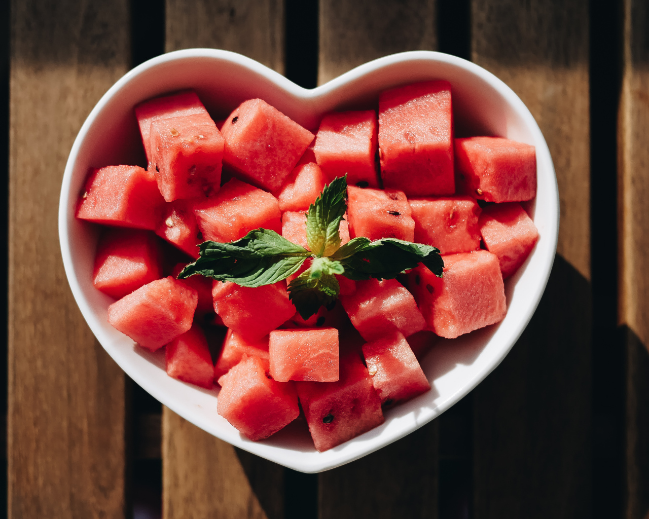 Нарезанный кубиками арбуз в белой тарелке в форме сердца