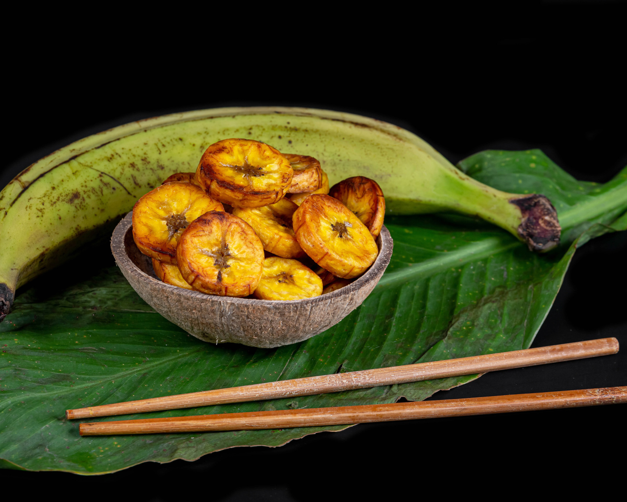 Сушеные бананы на столе с палочками и зеленым листом