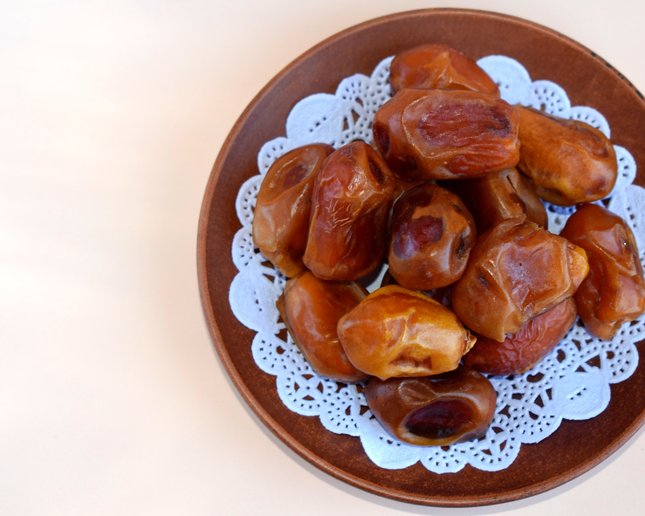 Сушеные финики в деревянной миске на белом фоне