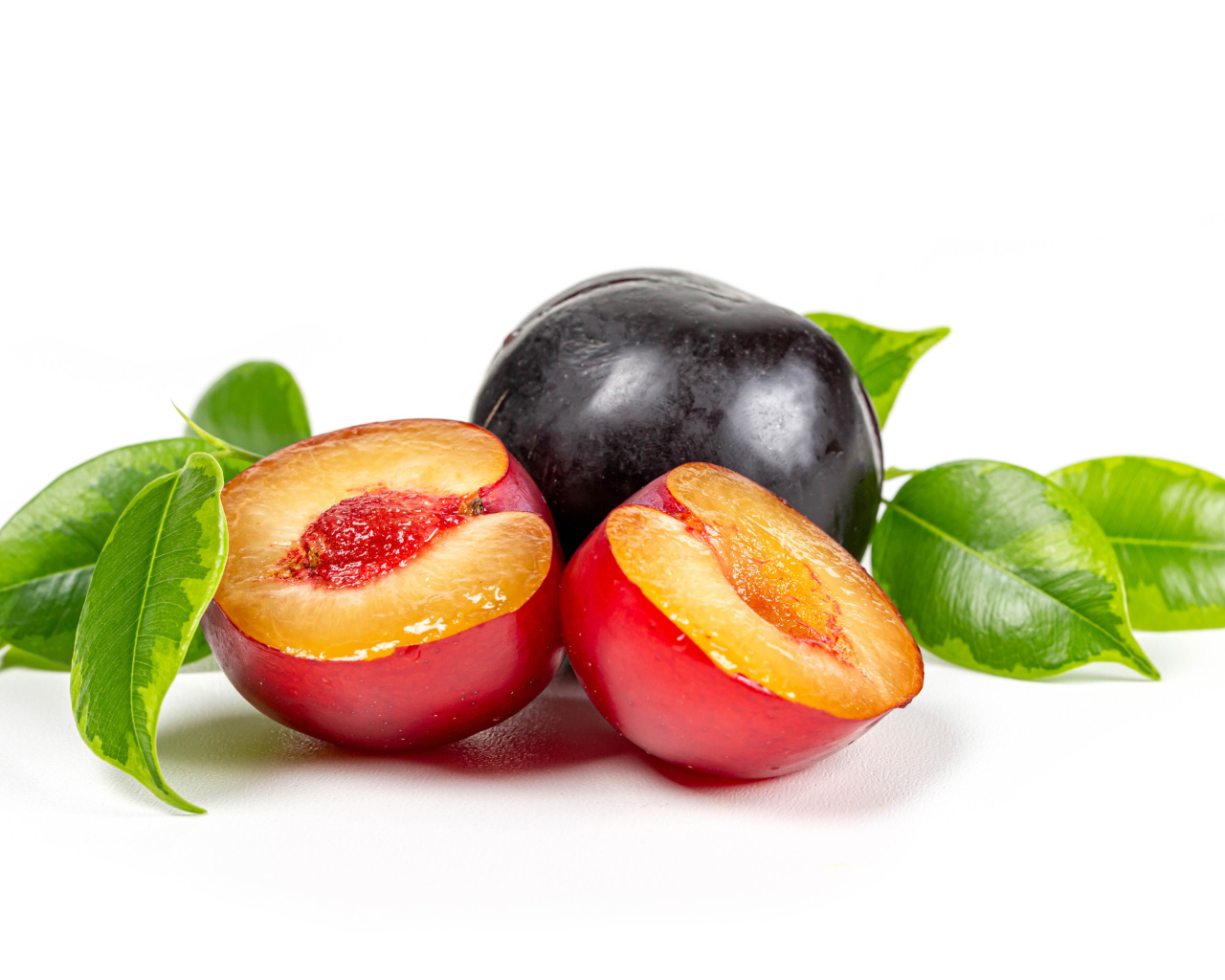 Сочные аппетитные сливы на белом фоне с зелеными листьями