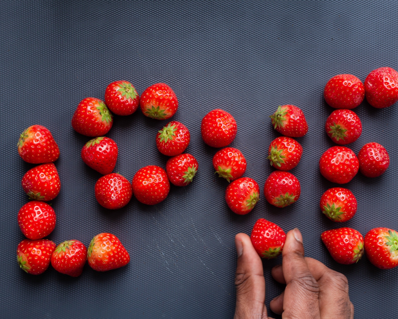 Надпись LOVE выложена из ягод спелой клубники 