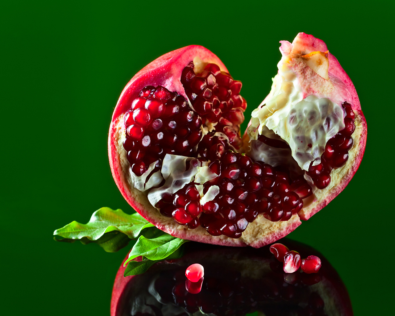 Очищенный гранат на зеленом фоне