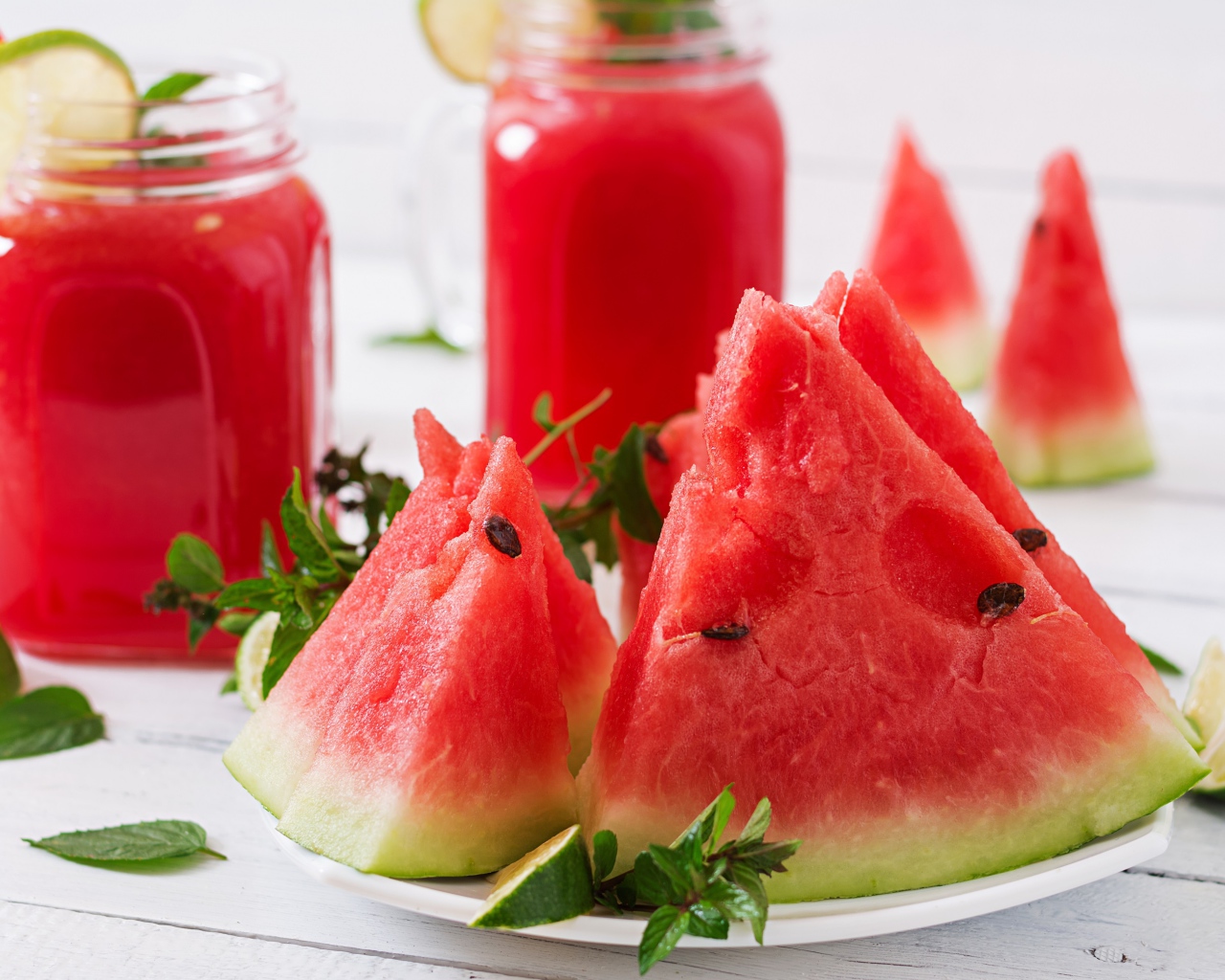 Куски арбуза с мятой на столе с соком 