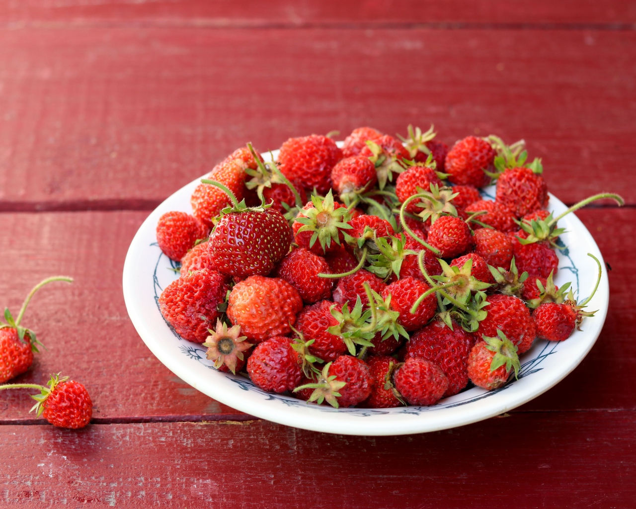 Тарелка со спелой домашней клубникой на столе