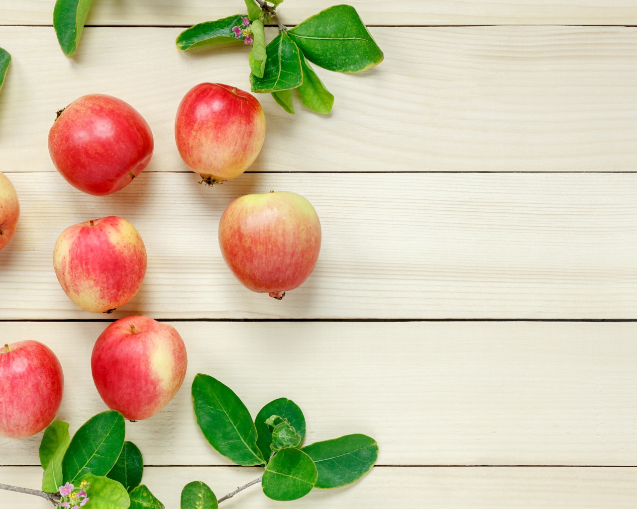Красные яблоки с зелеными листьями на деревянном столе 