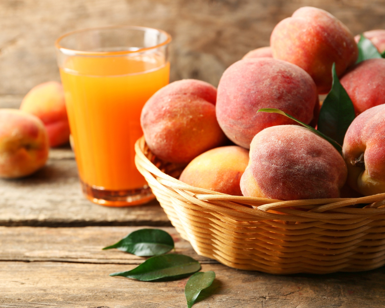 Спелые персики в корзине на столе с соком